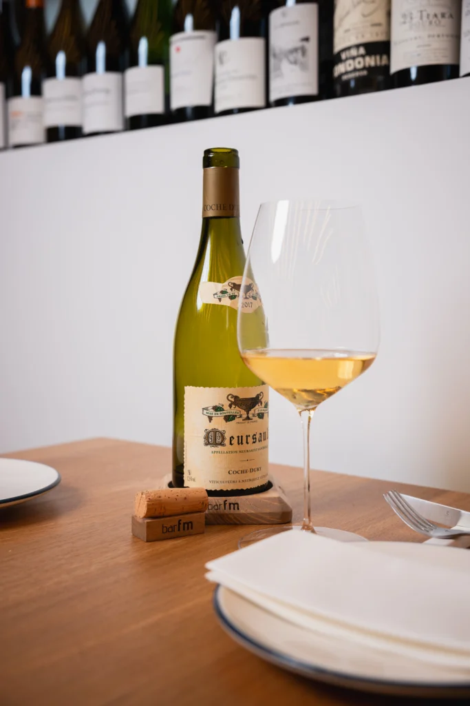 Botella de vino de Borgoña de la bodega Coche-Dury servida en mesa de Bar FM en Granada