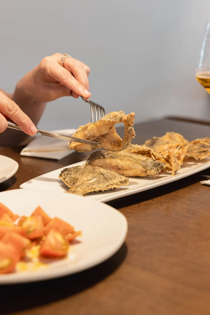 Cliente tomando un trozo de pescado frito en Bar FM Granada